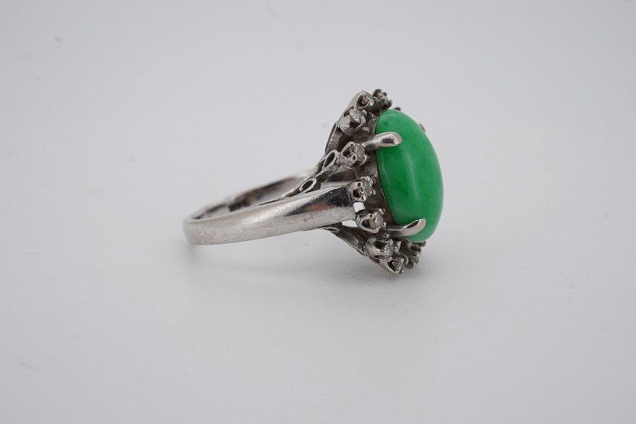 A white metal and cabochon jade set ring, with round cut diamond set border, size N, gross weight 5.4 grams. Condition - fair to good